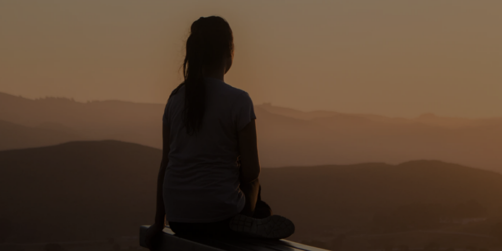 Woman reflects on her Scientology methods during dusk staring across the hills